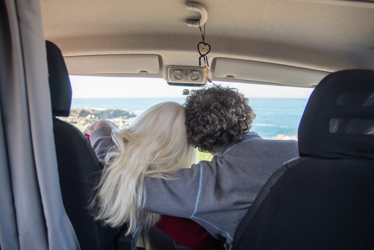 Back View of a Couple Sitting in a Campervan and Hugging 